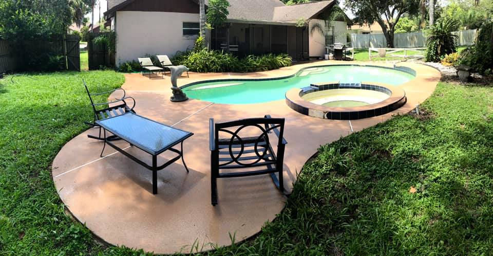Backyard pool area with freshly cleaned patio furniture and concrete surface, showcasing pressure washing services in Winter Park, FL.